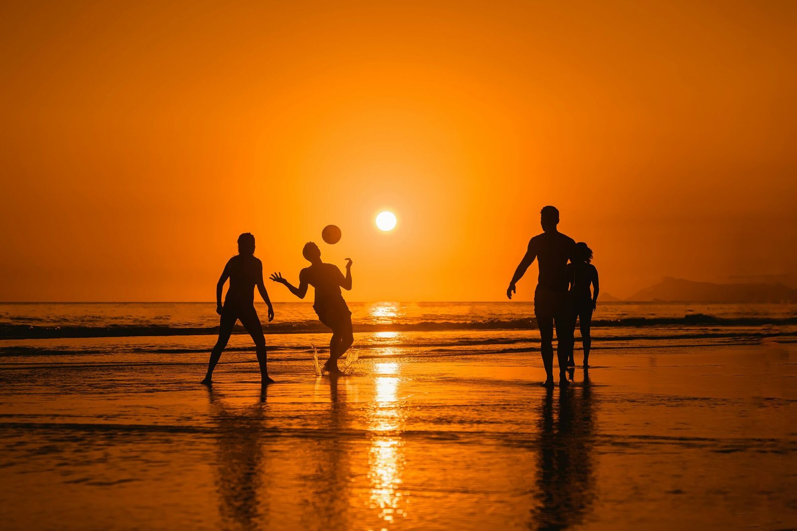 Friends playing on the beach at sunset
